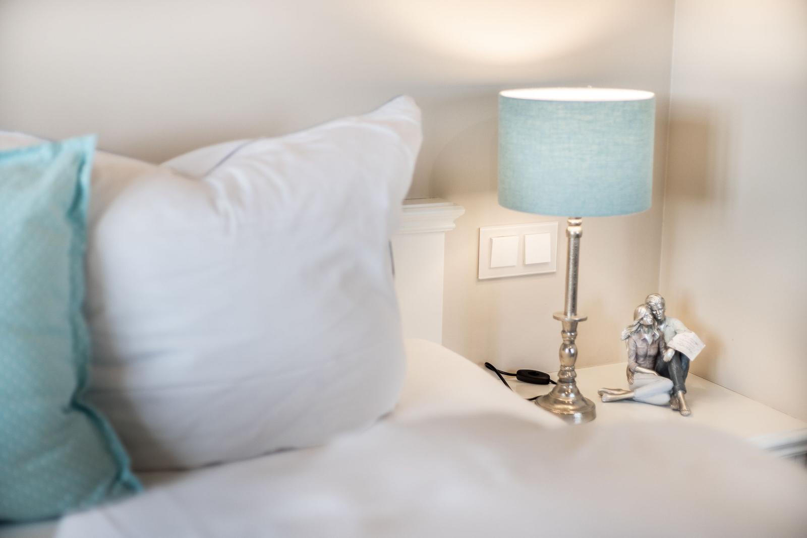 Bettkopfteil mit Kissen, Nachttisch mit Lampe und Figur
