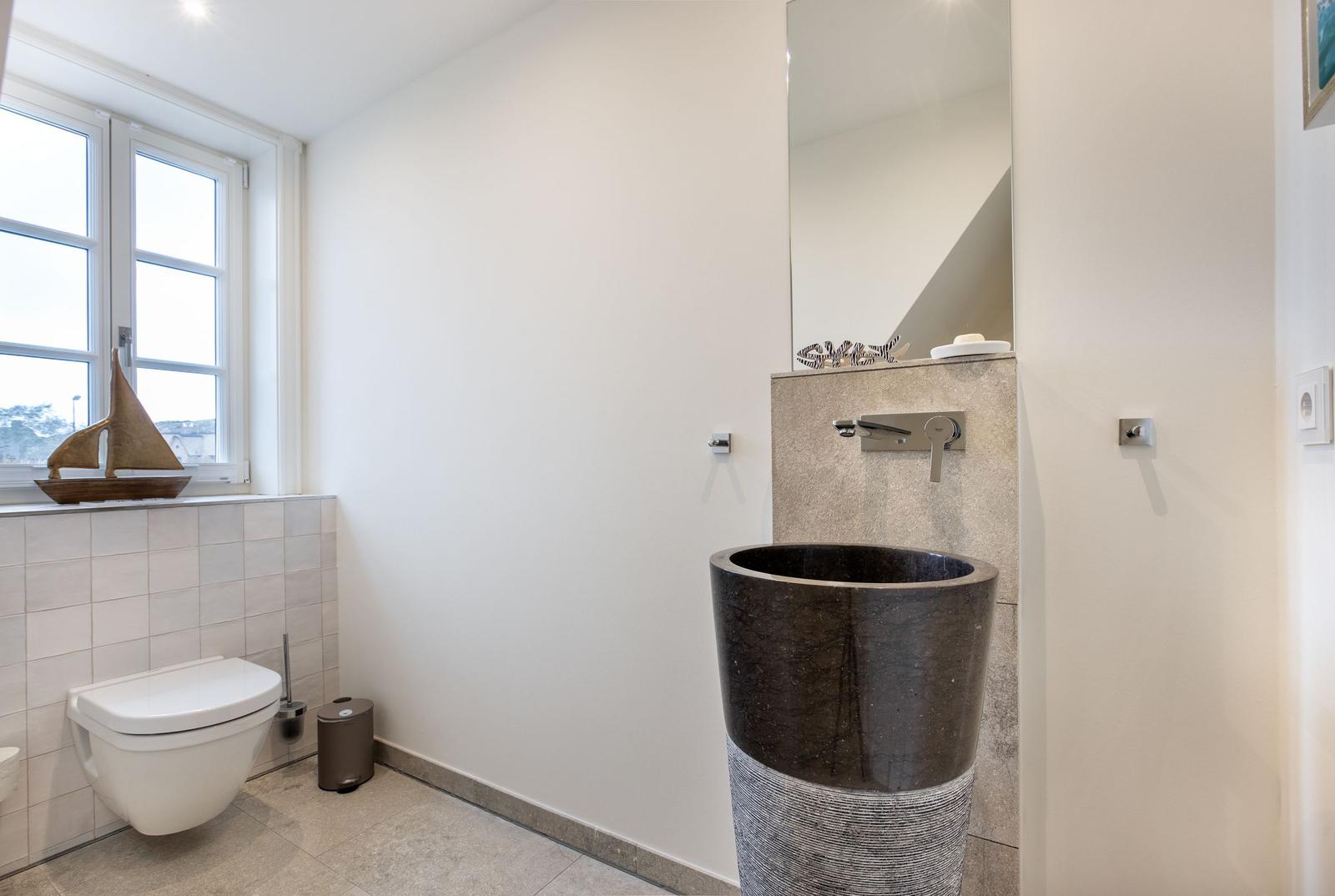Badezimmer mit Toilette, Waschbecken und Fenster.
