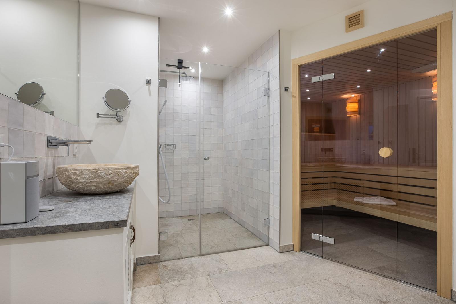 Badezimmer mit Dusche, Sauna und Steinwaschbecken.