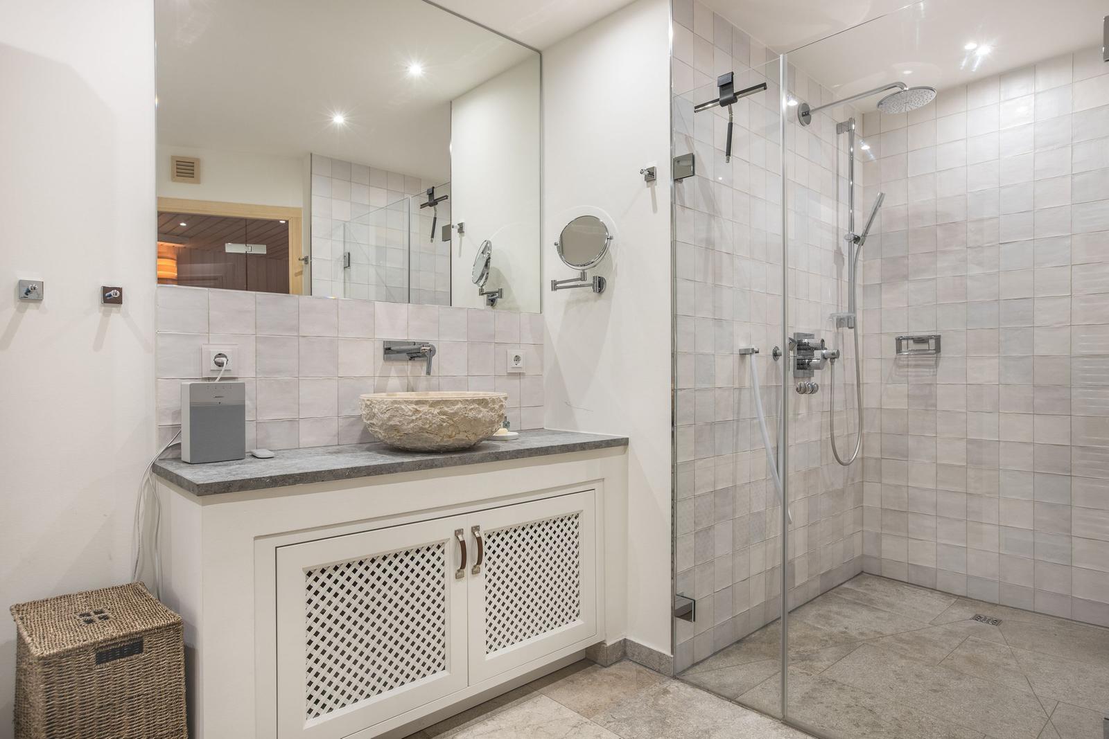 Badezimmer mit Dusche, Waschbecken und Spiegel