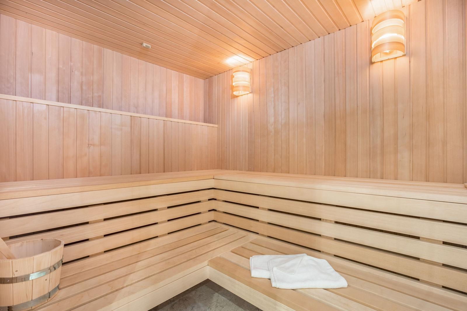Sauna mit Holzbank, Holzwand und weißen Handtüchern.