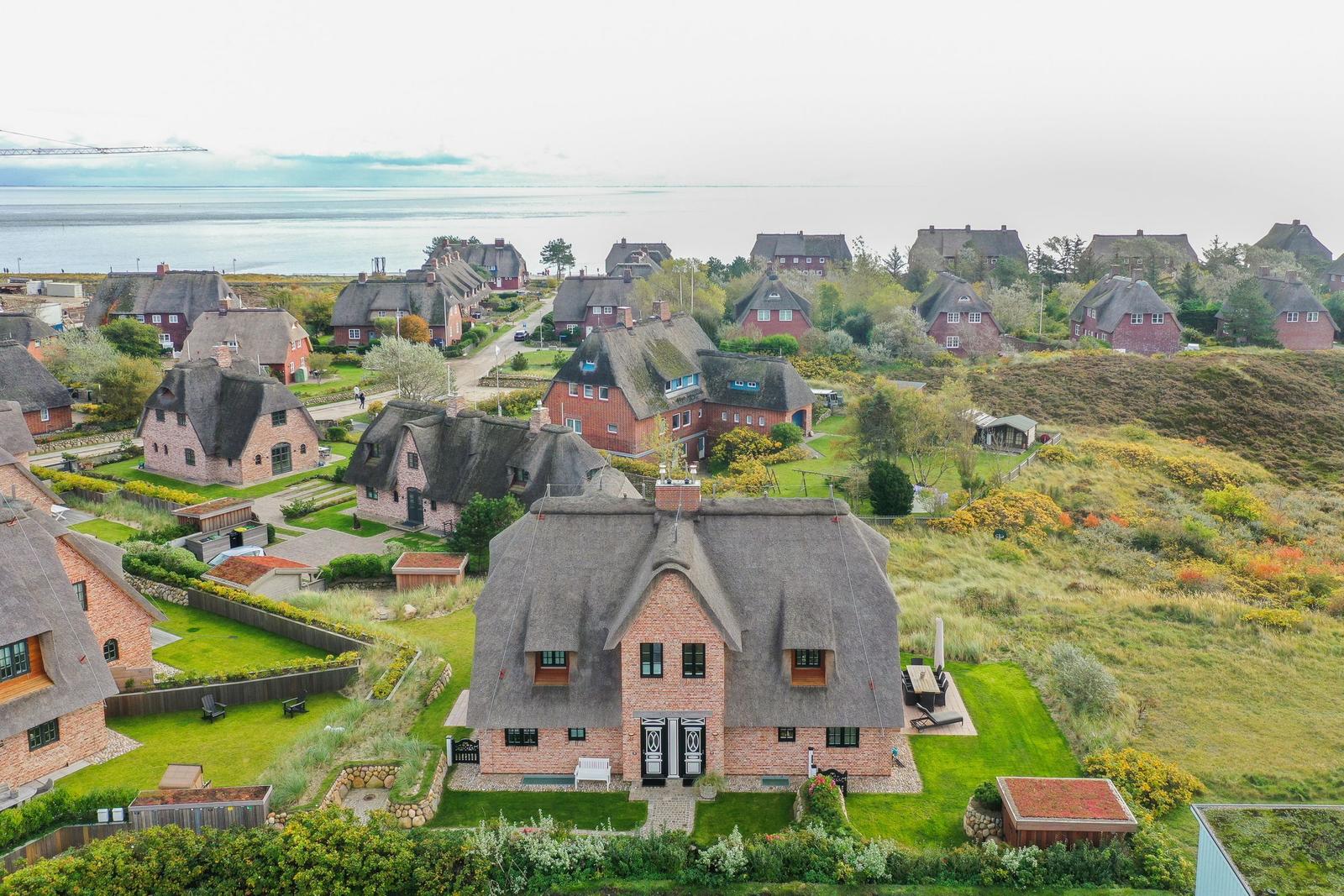 Dorfhaus mit Strohdach und Garten, Blick auf Meer und Landschaft.