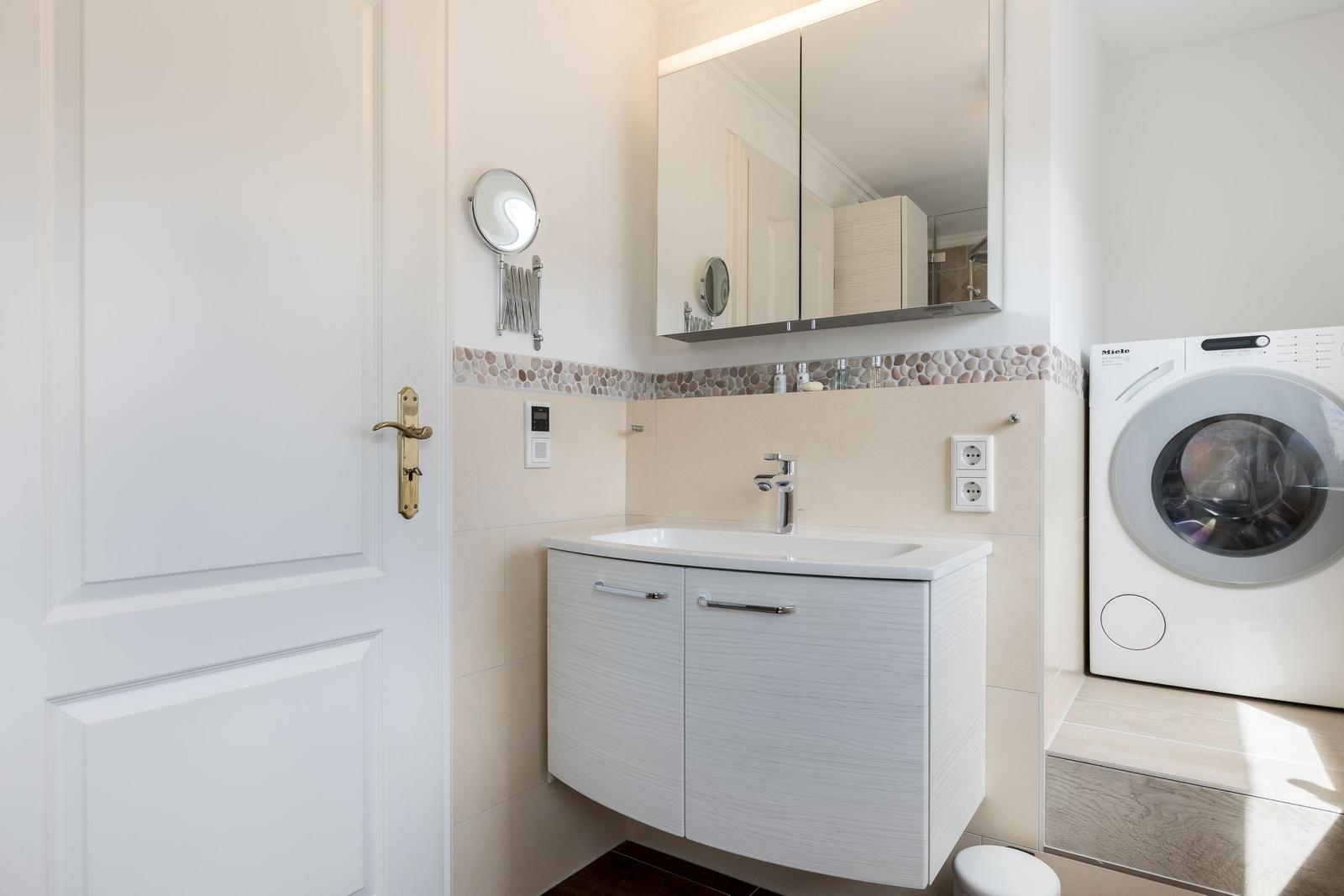 Badezimmer mit Waschmaschine und Spiegelschrank