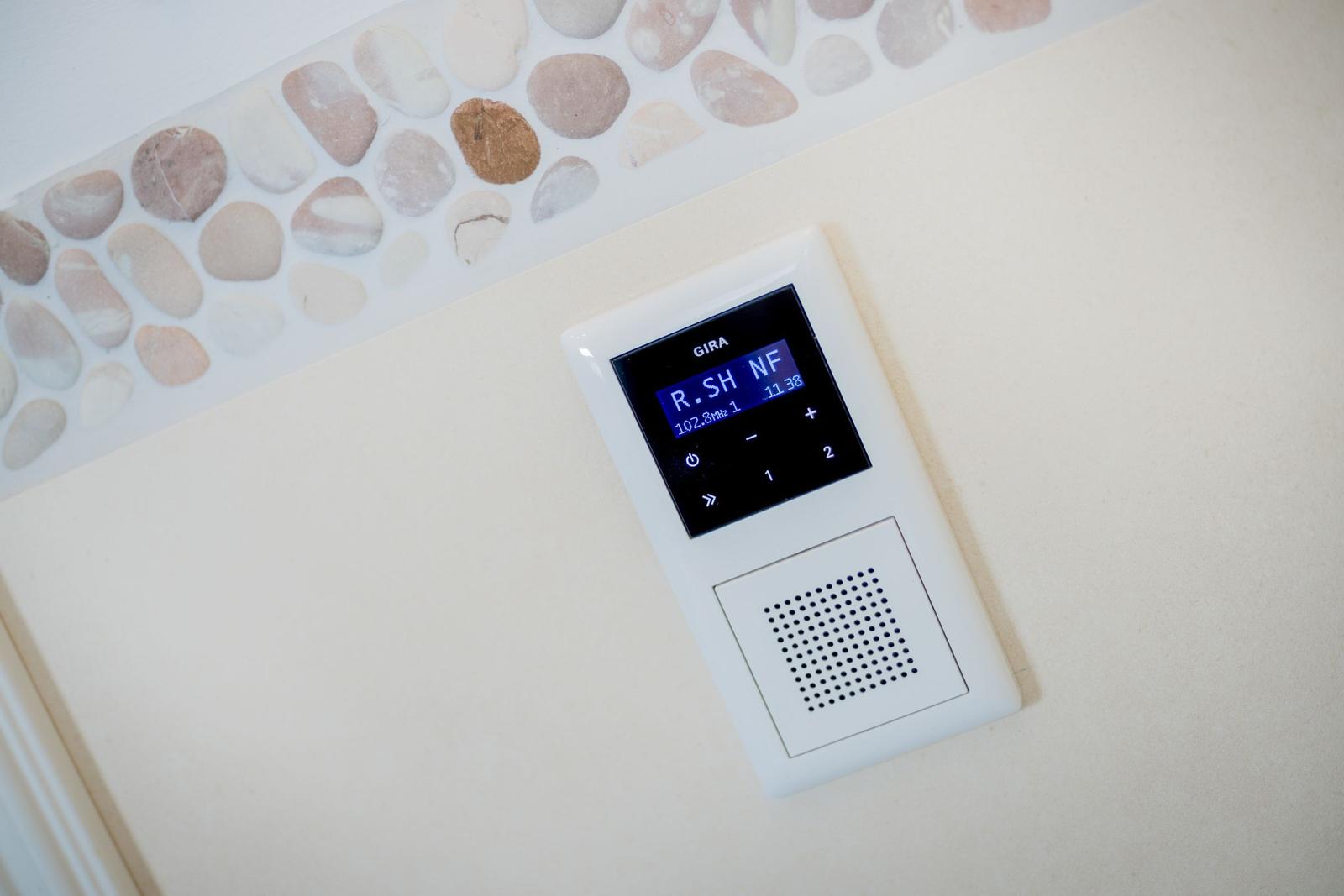 Wandmontierte Audio-Einheit mit Steuertasten und Display.