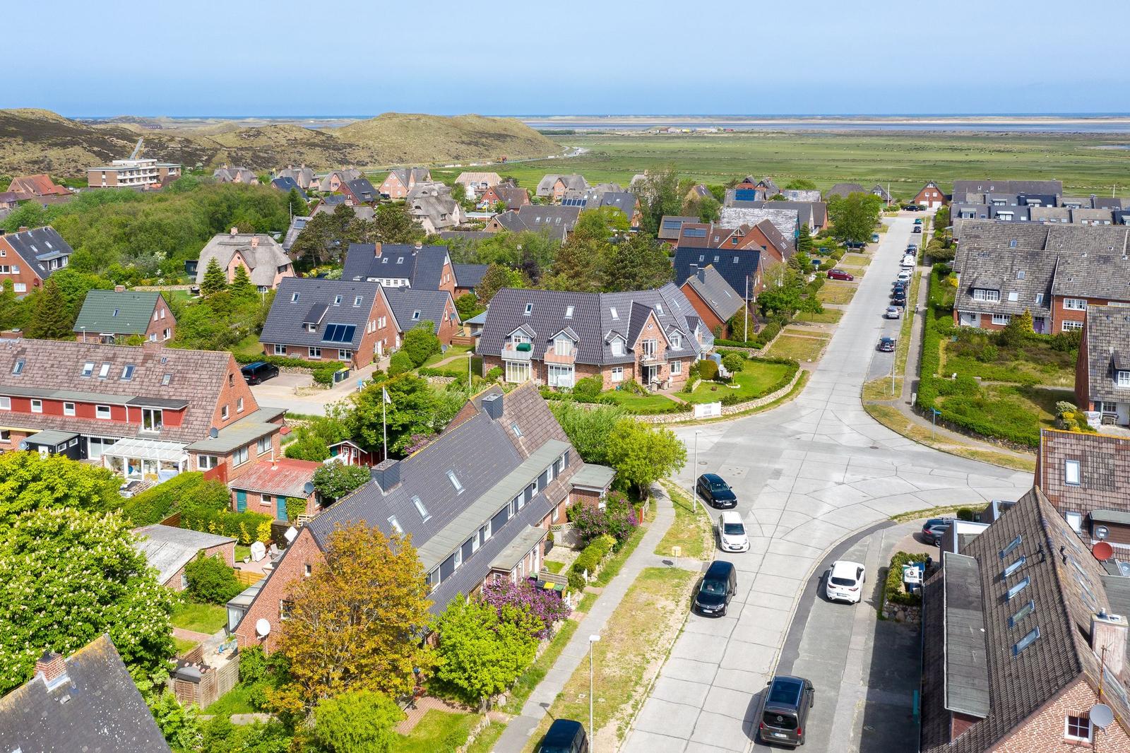 Aussicht auf Wohnsiedlung mit Häusern, Straßen und Grünflächen bis zum Horizont.