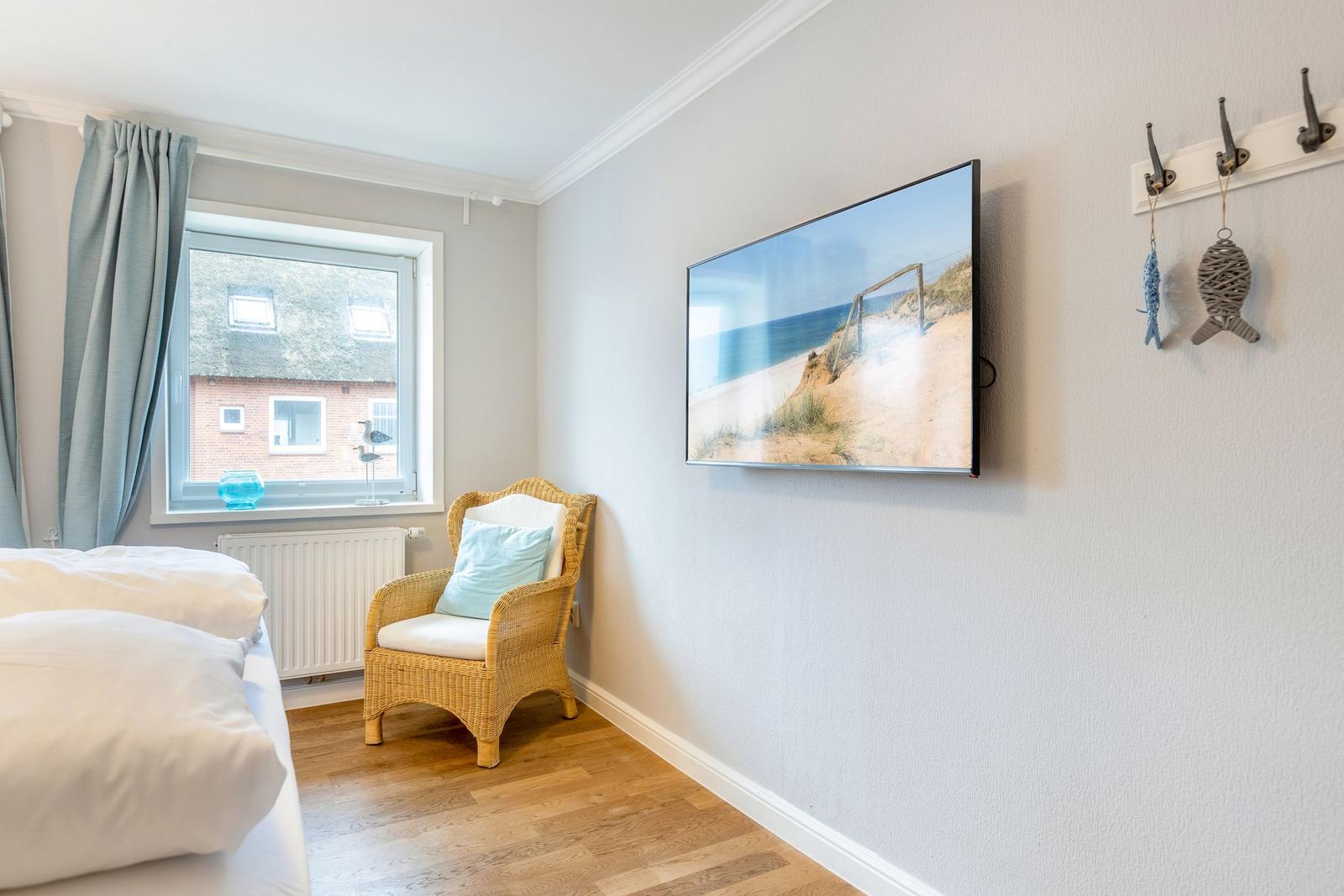 Bedroom with bed, chair, and TV mounted on the wall.