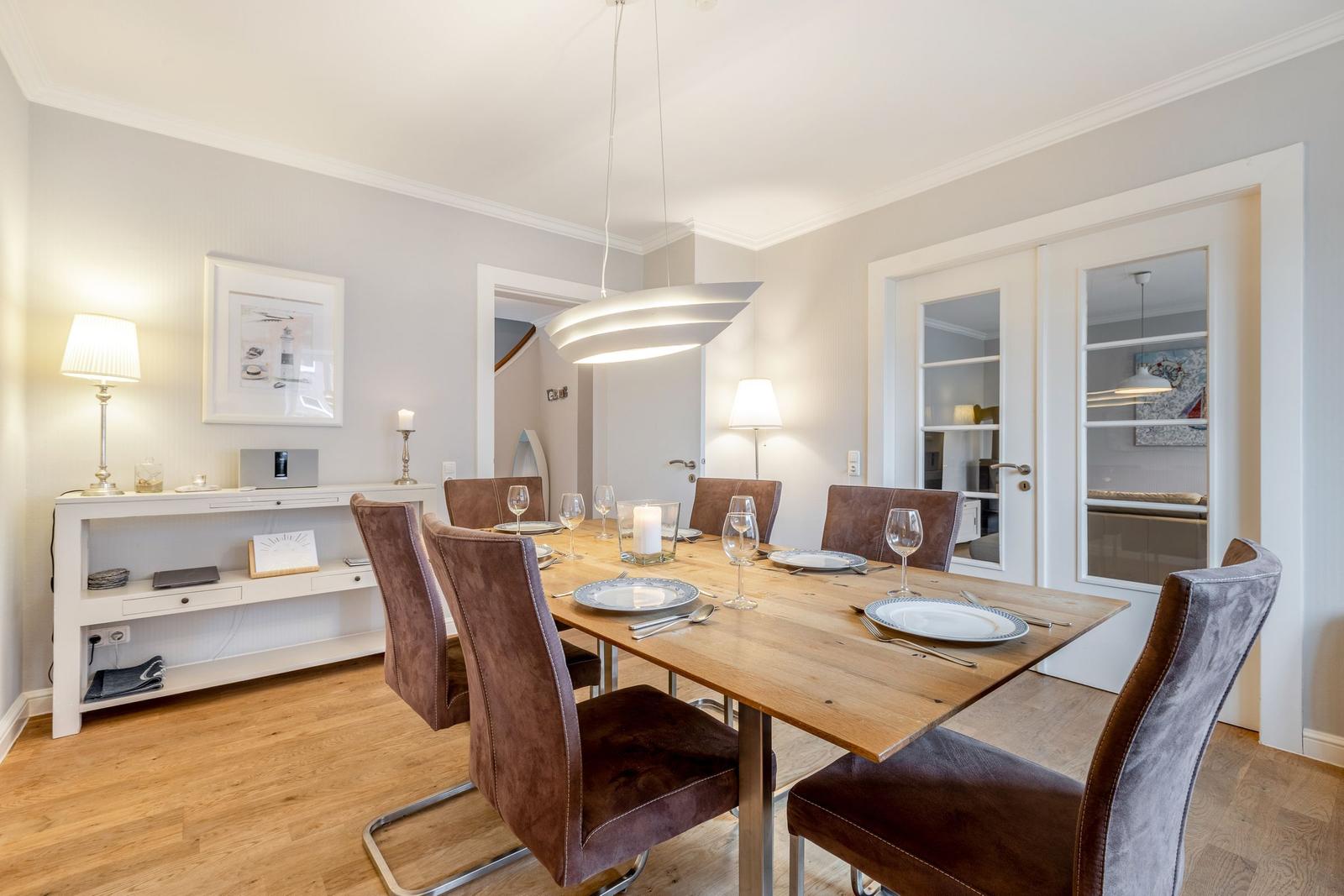 Dining room with wooden table, six chairs, and pendant light.