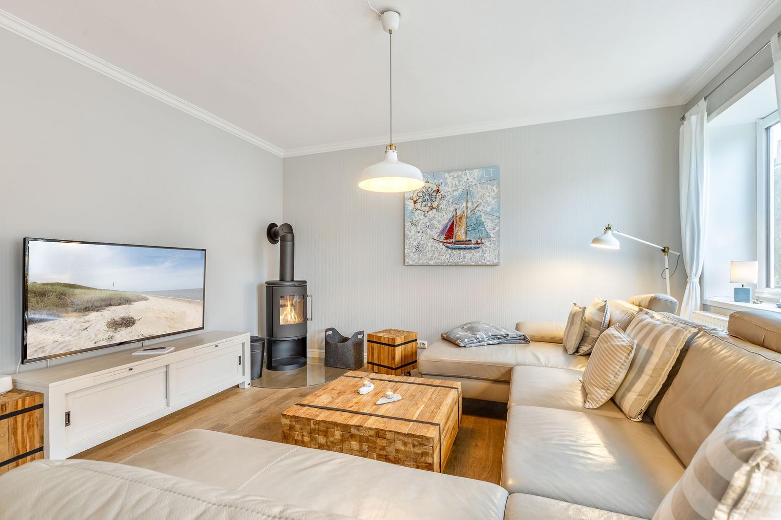 Living room with sofa, wood stove, TV, and wooden table.