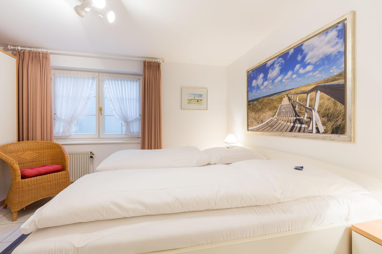 Bedroom with double bed, window, and wall picture.