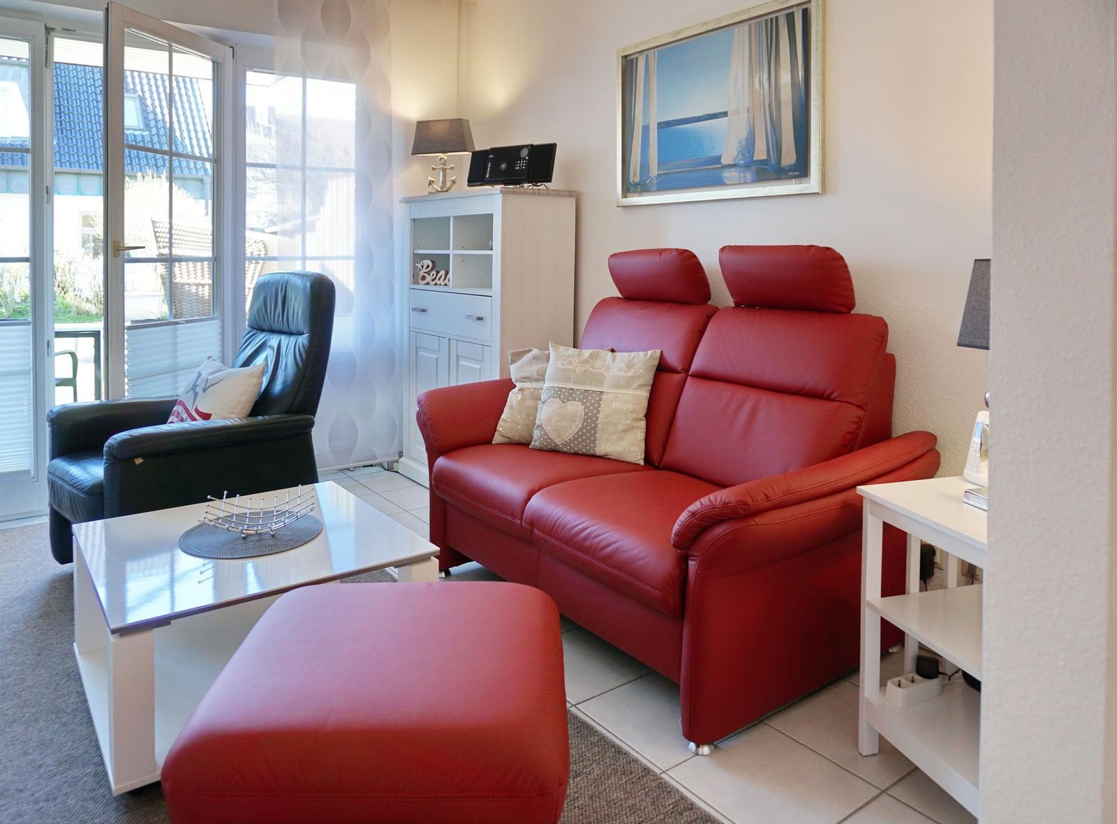 A living room with red sofa, black chair and glass table.