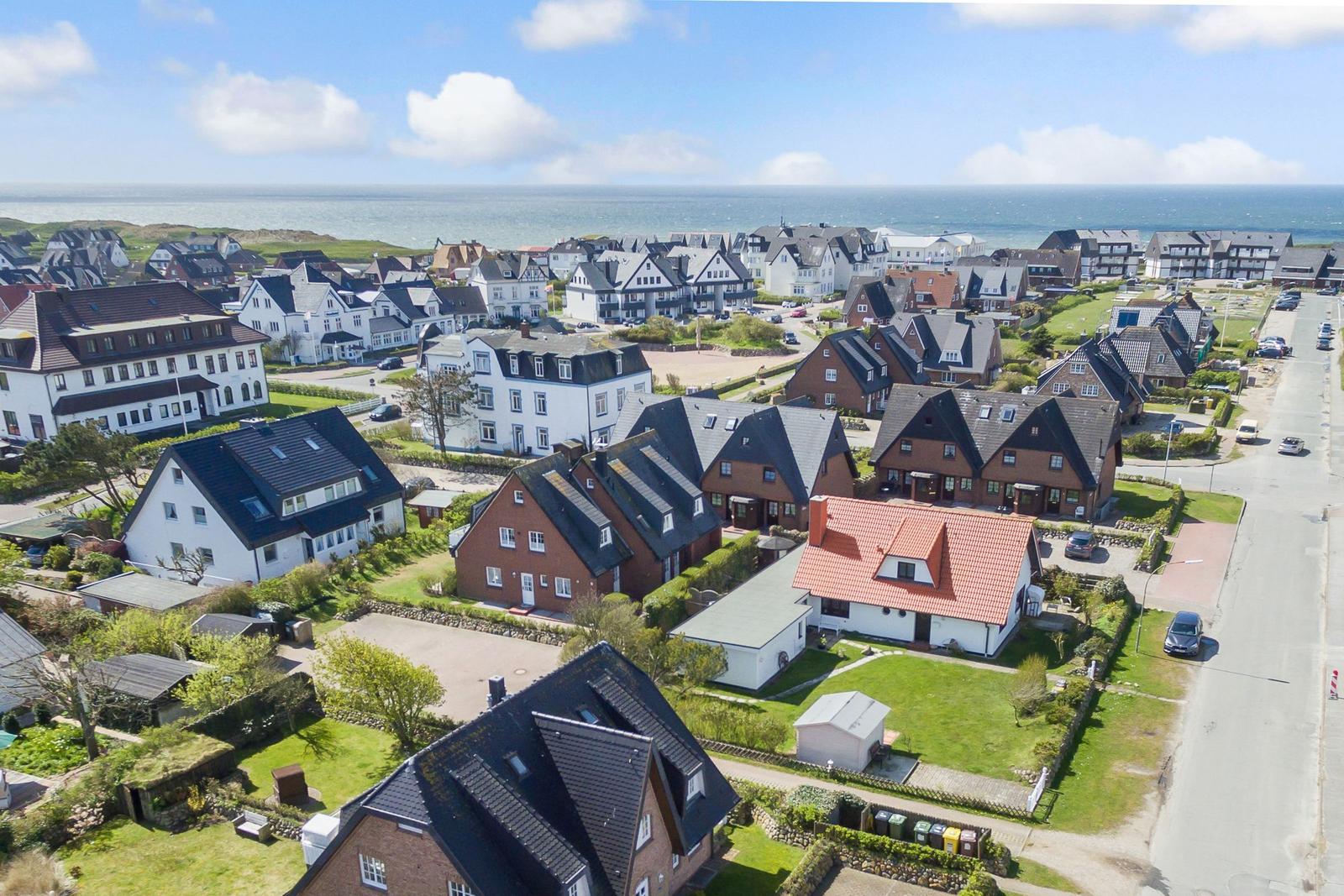 Aerial view of coastal village with houses and sea in background.