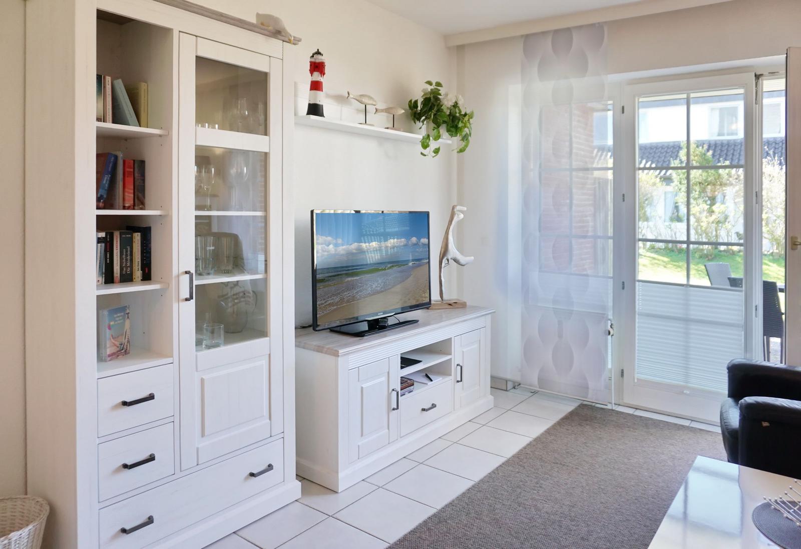 Living room with TV, bookcase, and view of balcony