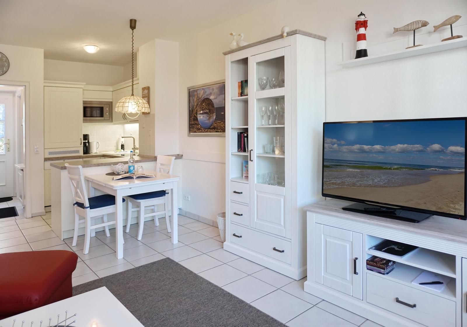 Living and dining area with TV, cabinet, and kitchenette.