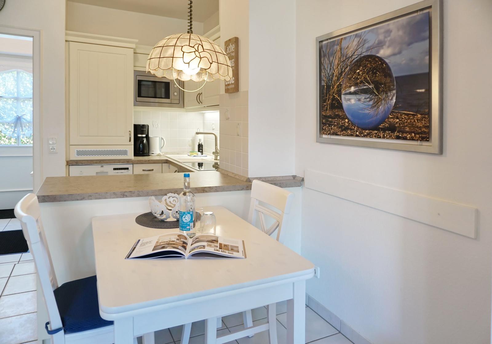 Dining area with table, chairs, and kitchen in the background.