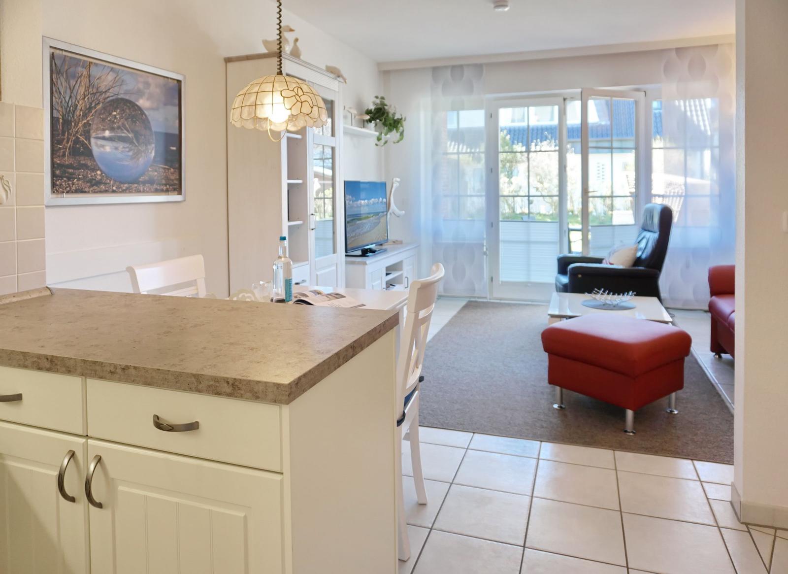 Kitchen with dining area and living room with red armchair and TV.