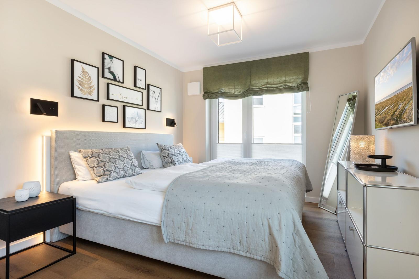 Schlafzimmer mit Doppelbett, Wandbildern und Fenster mit Blick.