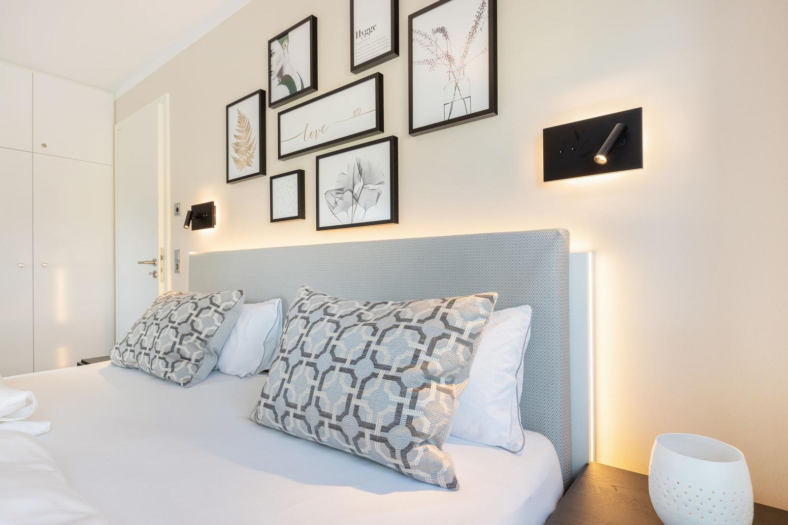Schlafzimmer mit Bett, Wandbildern und Nachttischlampe.