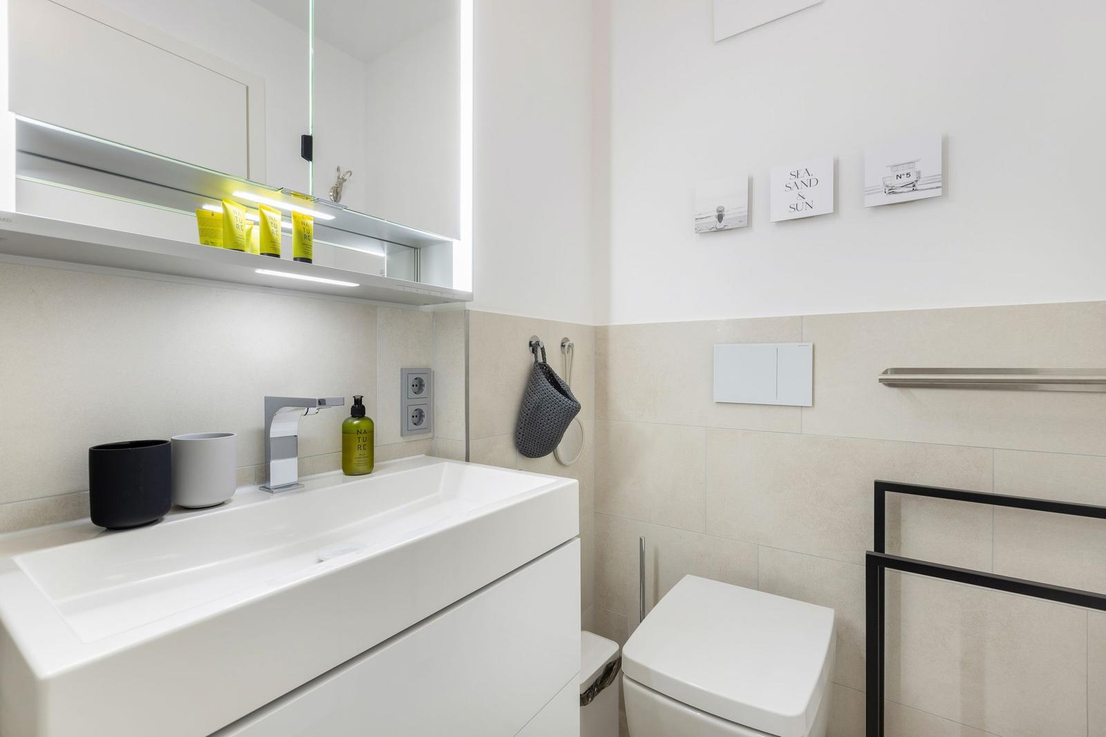 Moderne Badezimmer mit Waschbecken, Spiegel und Toilette.