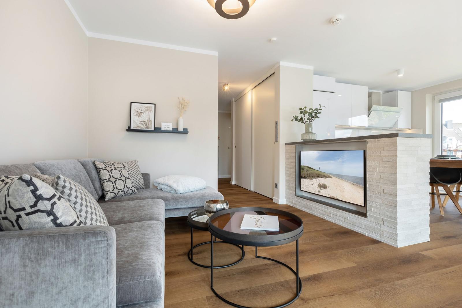 Wohnbereich mit Sofa, Couchtisch und Küchenbereich mit Steinwand