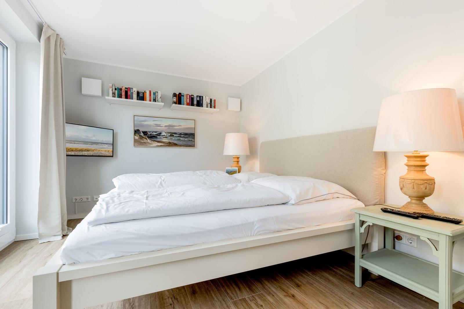 Schlafzimmer mit Bett, Nachttisch und Wandregalen.