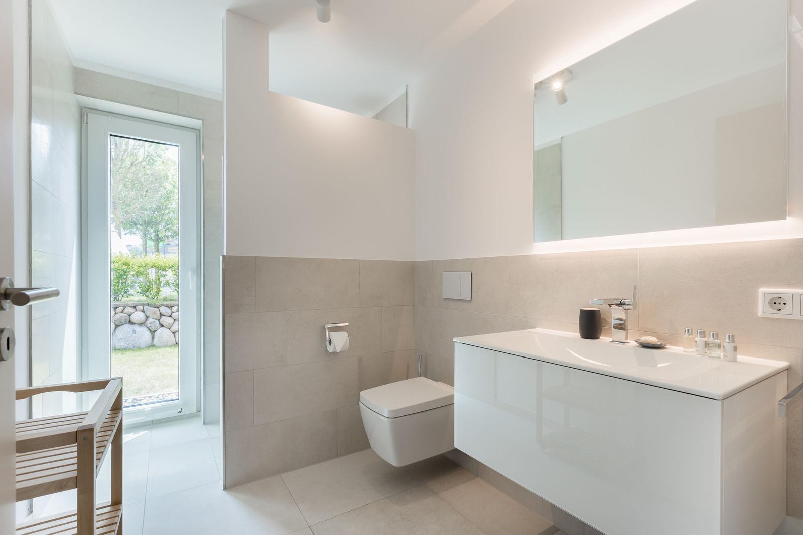 Badezimmer mit Toilette, Waschbecken und Fenster zur Außenseite.