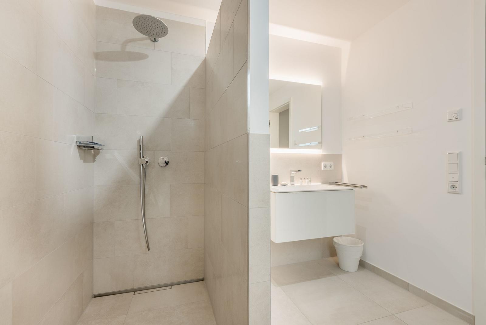 Dusche mit Duschbrause und Waschbecken mit Spiegel
