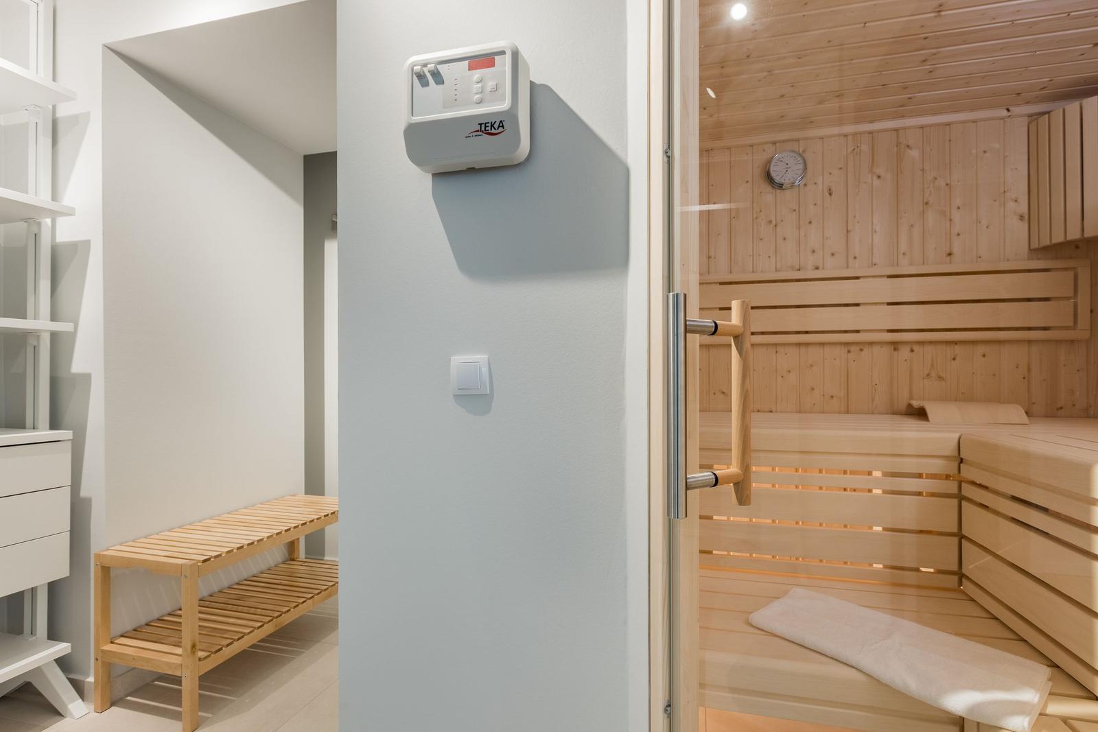 Sauna mit Holzbank und Thermostat an der Wand