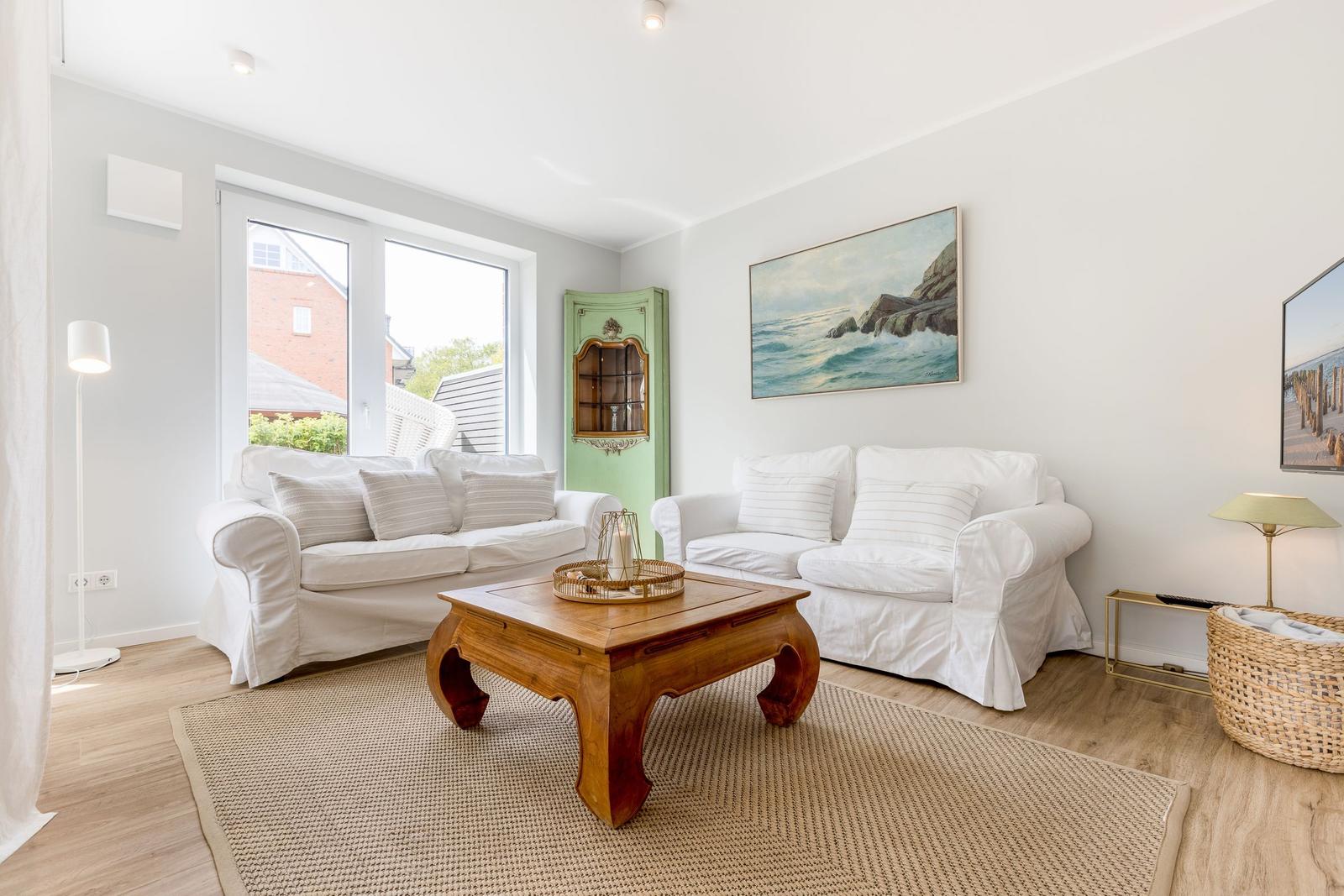 Wohnzimmer mit zwei weißen Sofas, Holzcoffee-Tisch und Wandbild.
