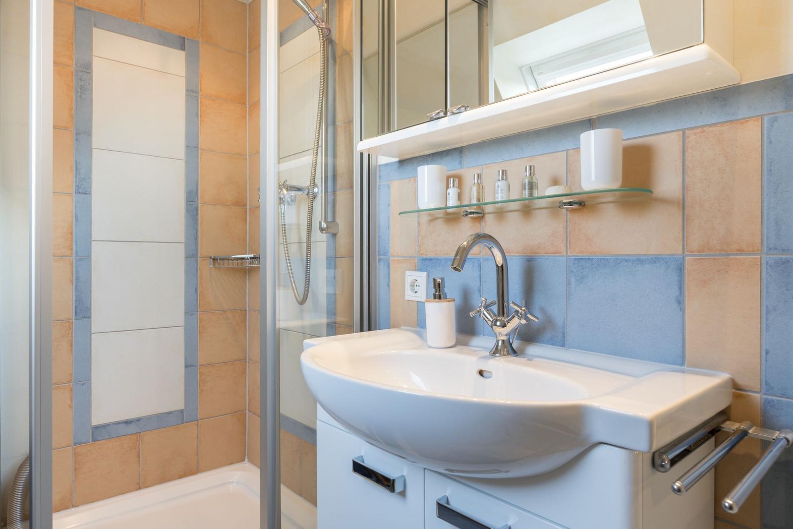 Badezimmer mit Dusche, Waschbecken und Spiegel
