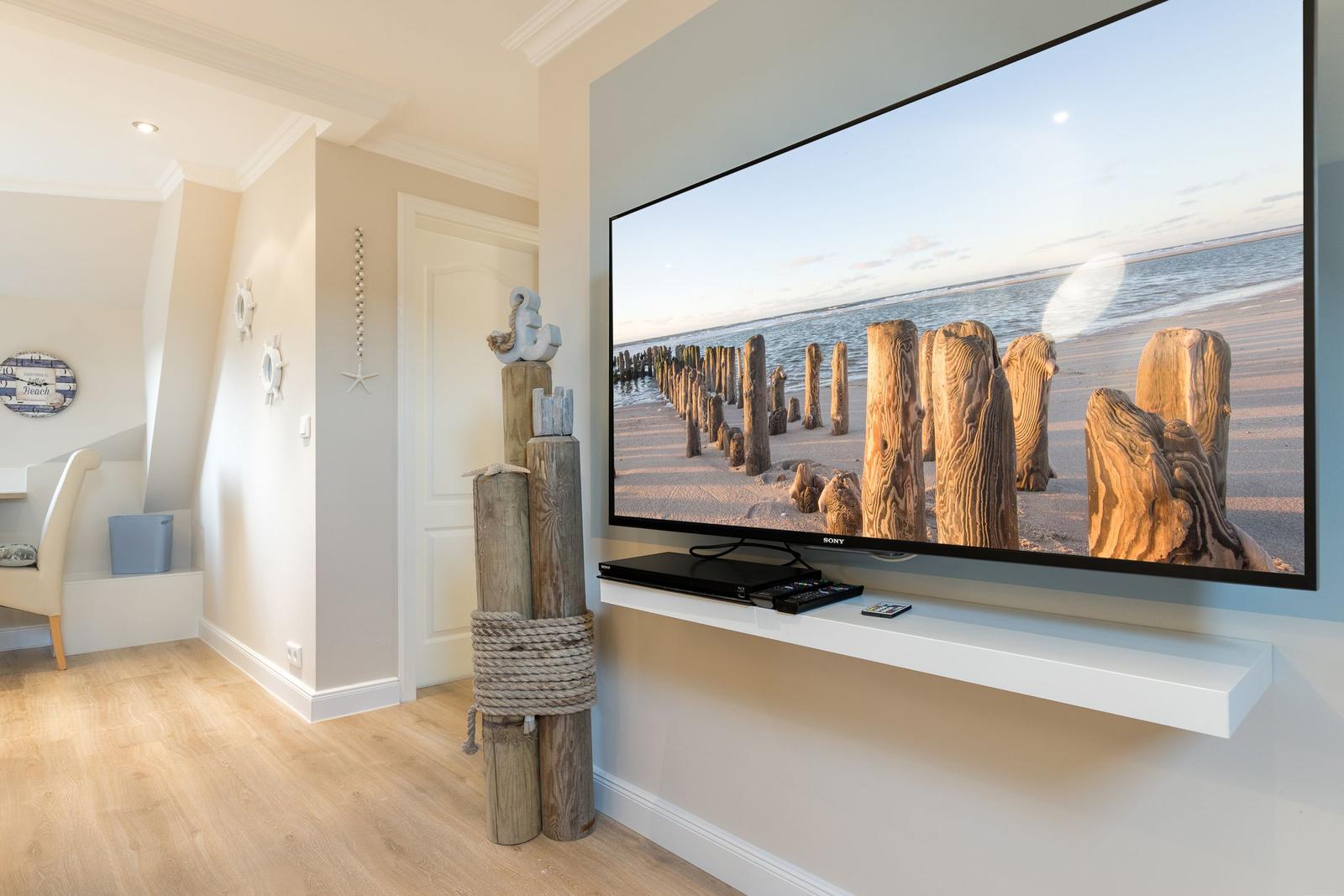 Großer Fernseher mit Strandbild, Holzpfosten-Dekoration und heller Holzboden