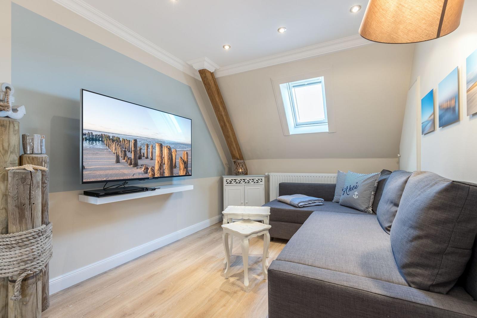 Wohnzimmer mit Sofa, Fernseher und Dachfenster.