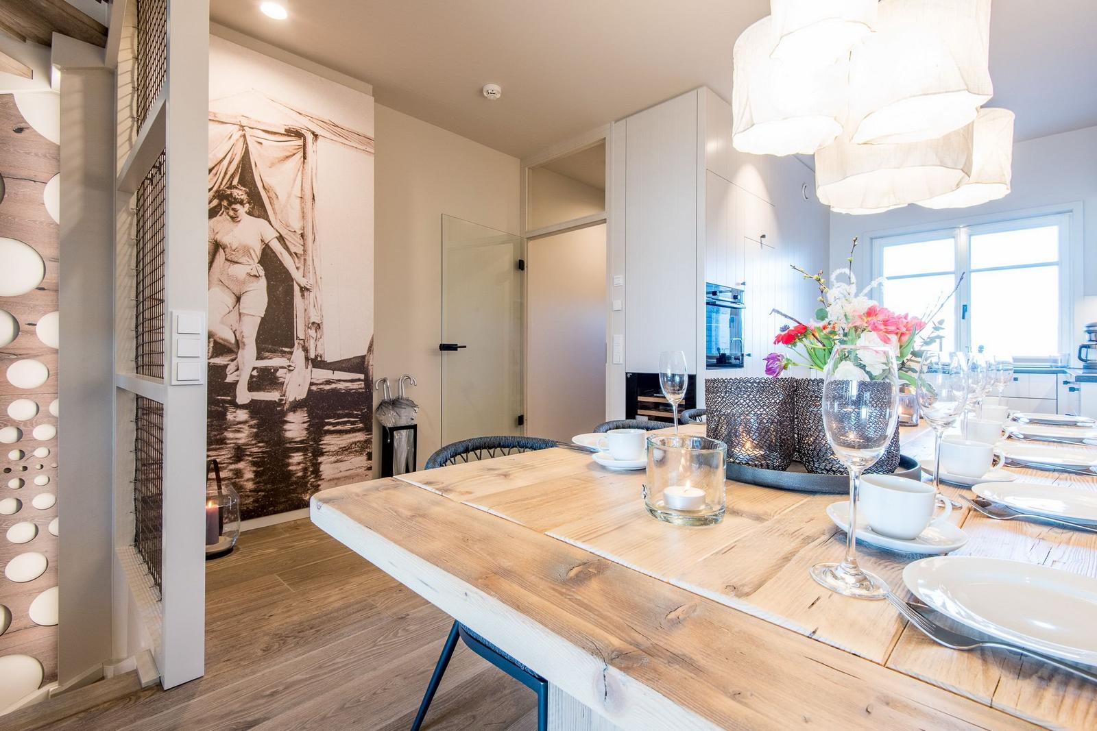 Esszimmer mit Holztisch, Stühlen und Blumendekoration.
