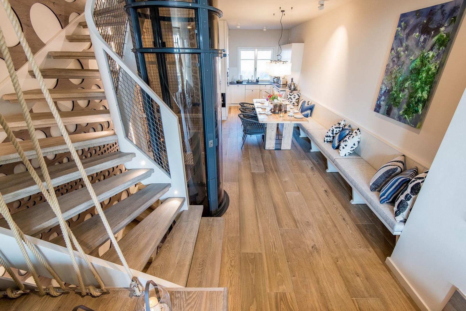 Eingangsbereich mit Treppe, Aufzug und Essbereich mit Sitzbank.