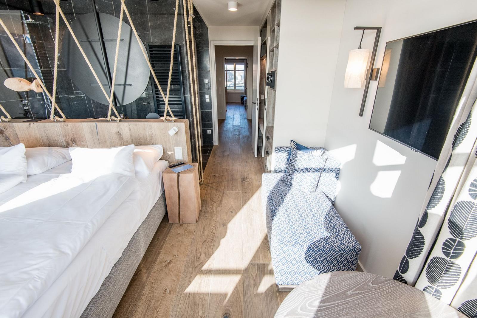 Schlafzimmer mit Bett, Sofa und Duschbereich.