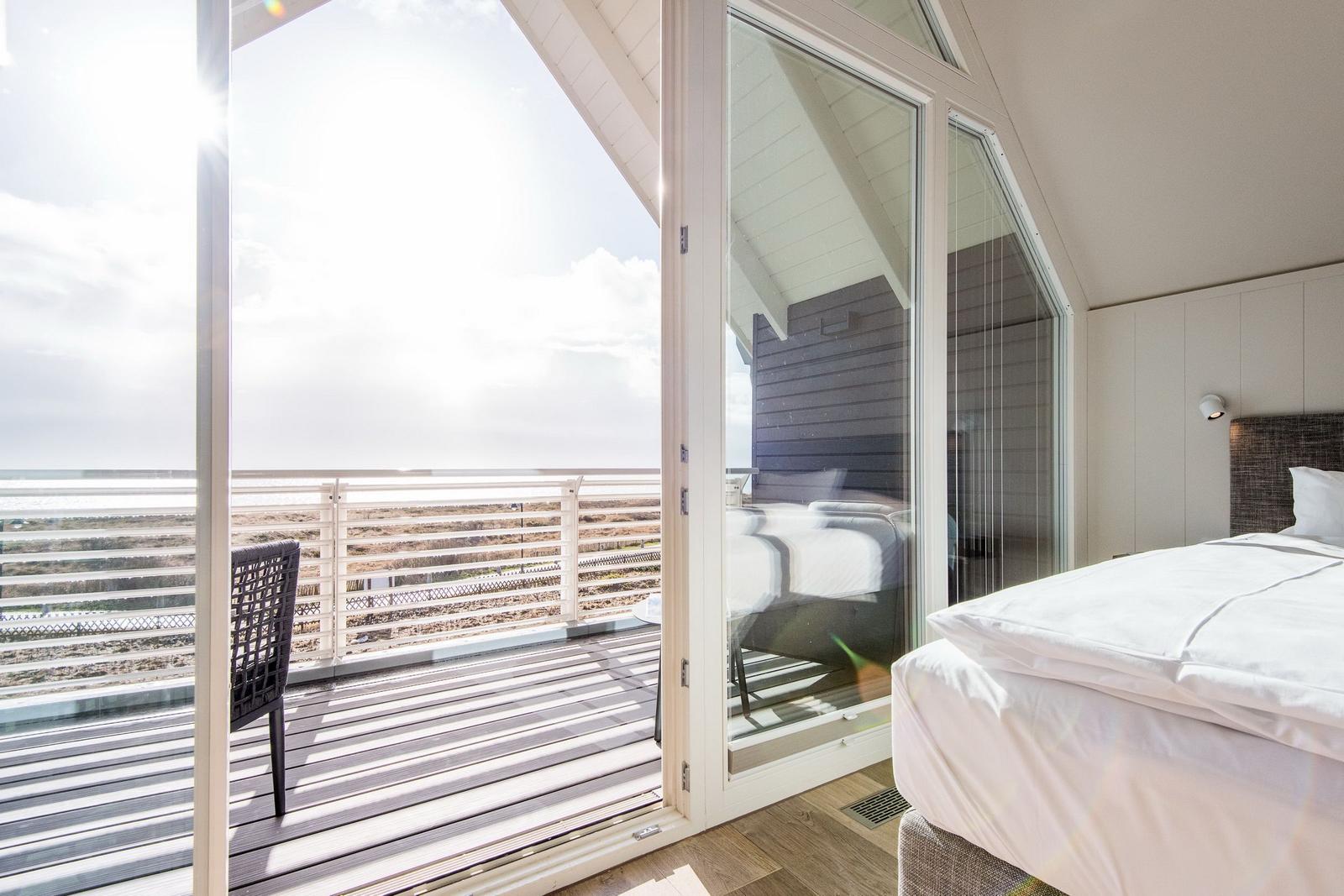 Schlafzimmer mit Balkon und Meerblick durch große Glasschiebetüren.