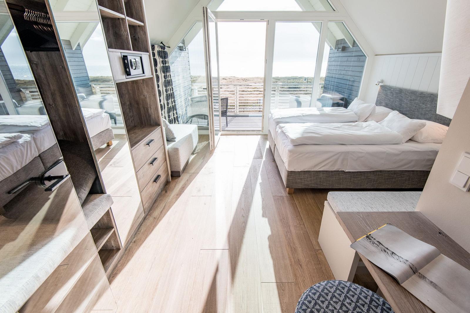 Schlafzimmer mit Doppelbett, Balkon und Holzboden.