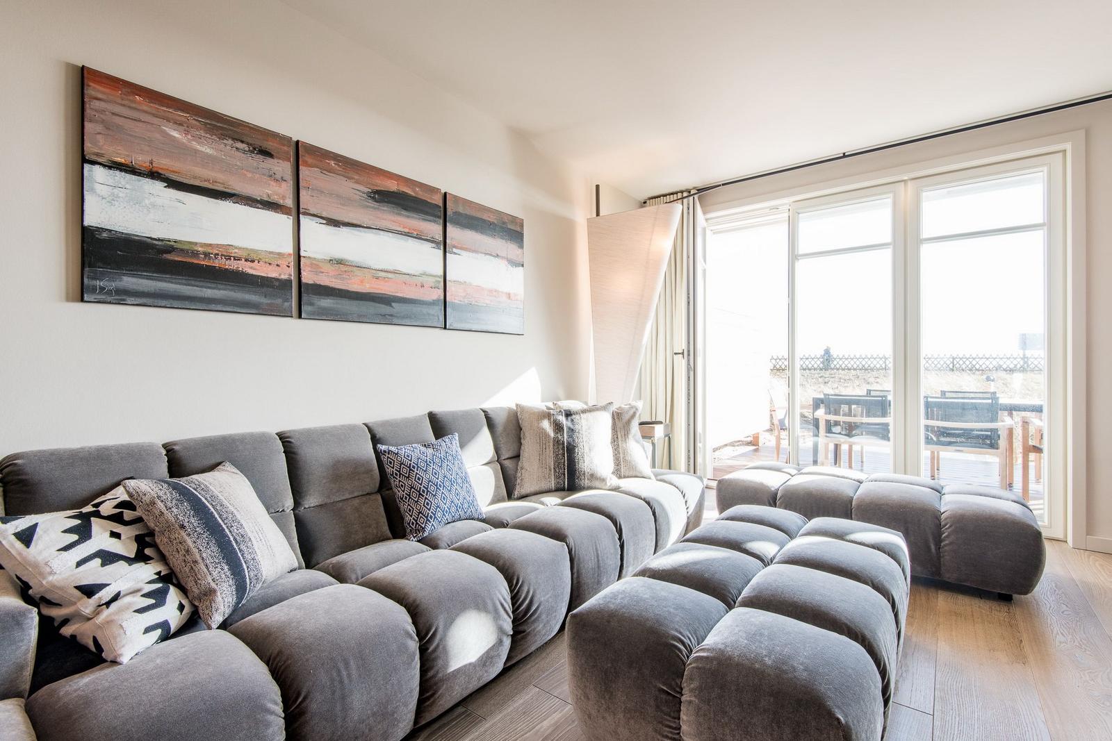 Großer Wohnbereich mit grauem Sofa und moderner Wanddekoration.