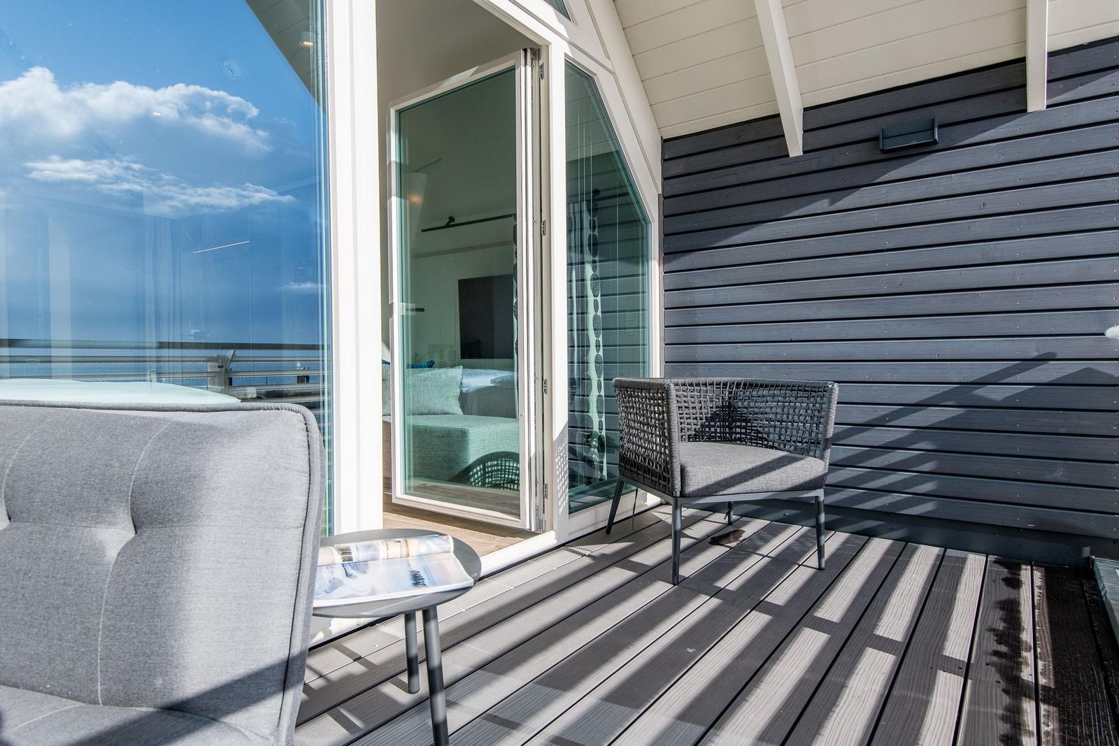 Terrasse mit Sitzgelegenheit und Meerblick durch Glasfront