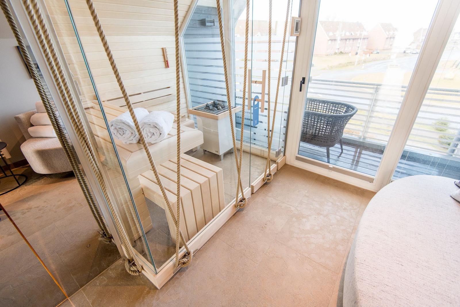 Sauna mit Glaswand und Außenterrasse mit Sitzgelegenheit.