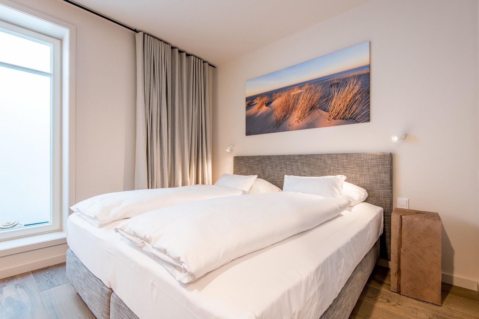 Schlafzimmer mit Doppelbett, Fenster und Wandbild.
