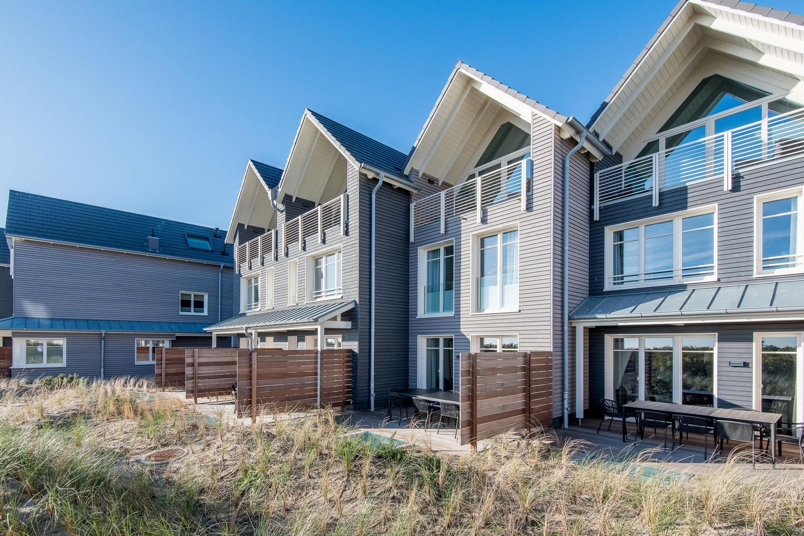 Moderne Ferienhäuser mit Balkonen und Terrassen im Strandbereich.