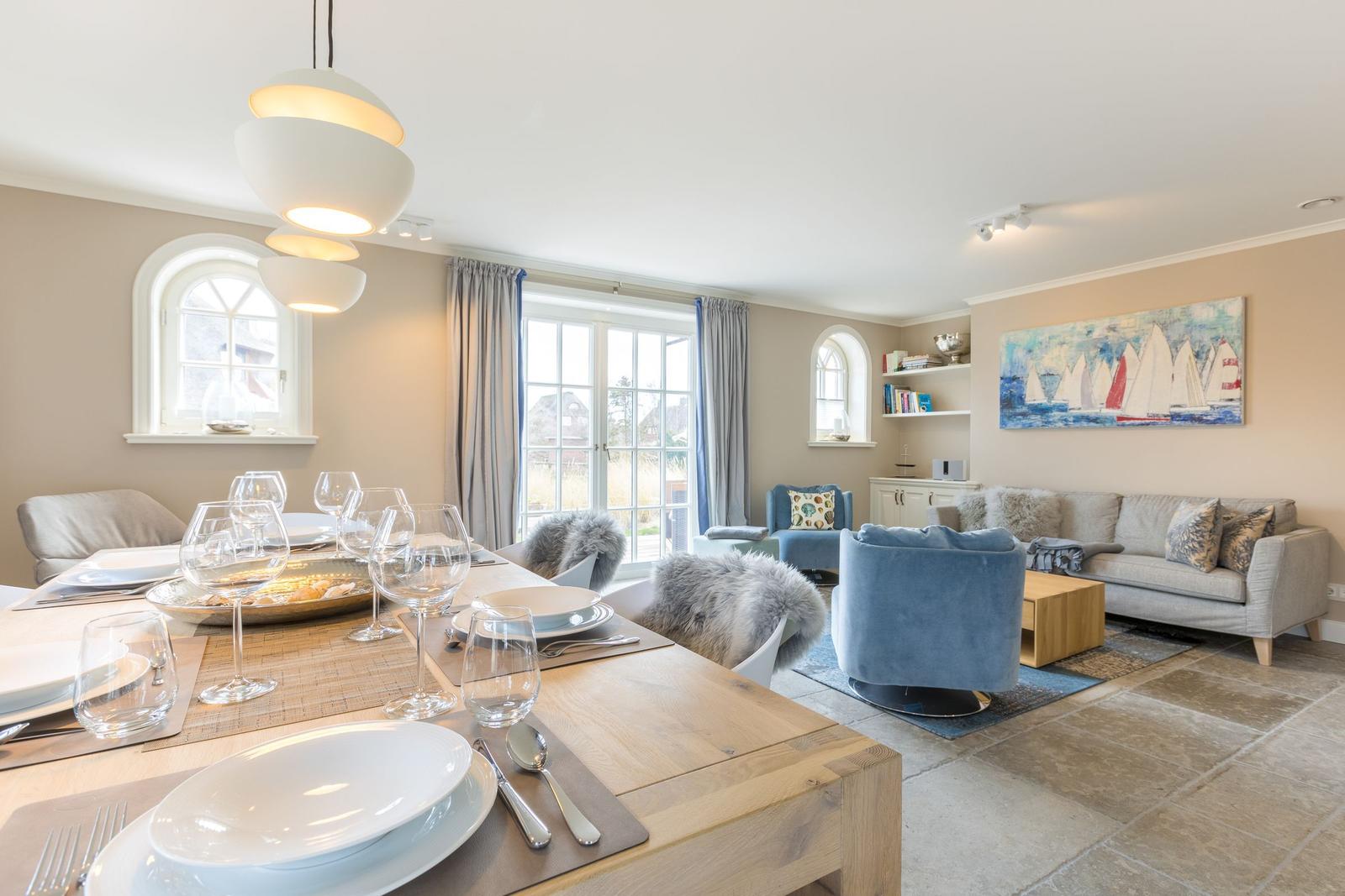 Essbereich mit Tisch und Stühlen, Wohnzimmer mit Sofa und Kissen.