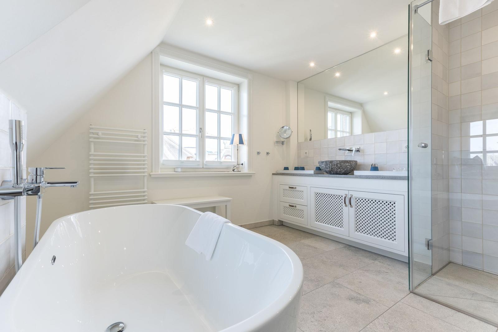 Dusche, Badewanne und Waschbecken in einem hellen Badezimmer mit Fenster und Spiegel.