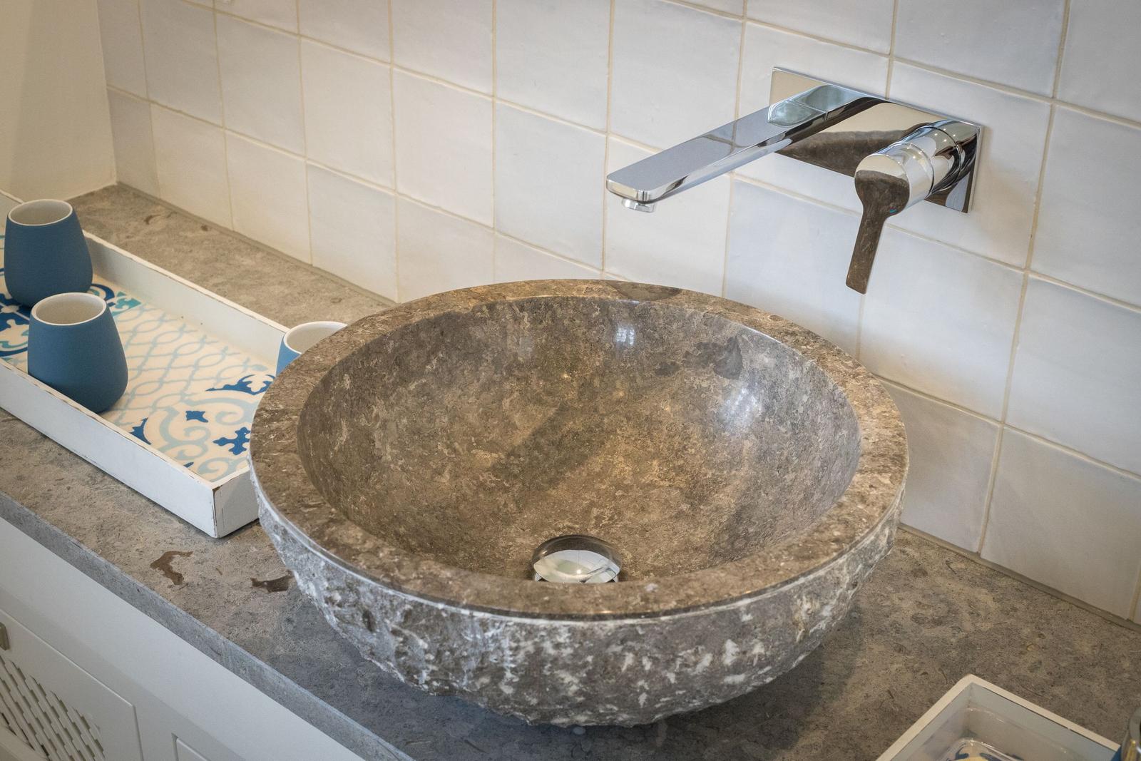 Steinspüle mit modernem Wasserhahn auf Arbeitsfläche