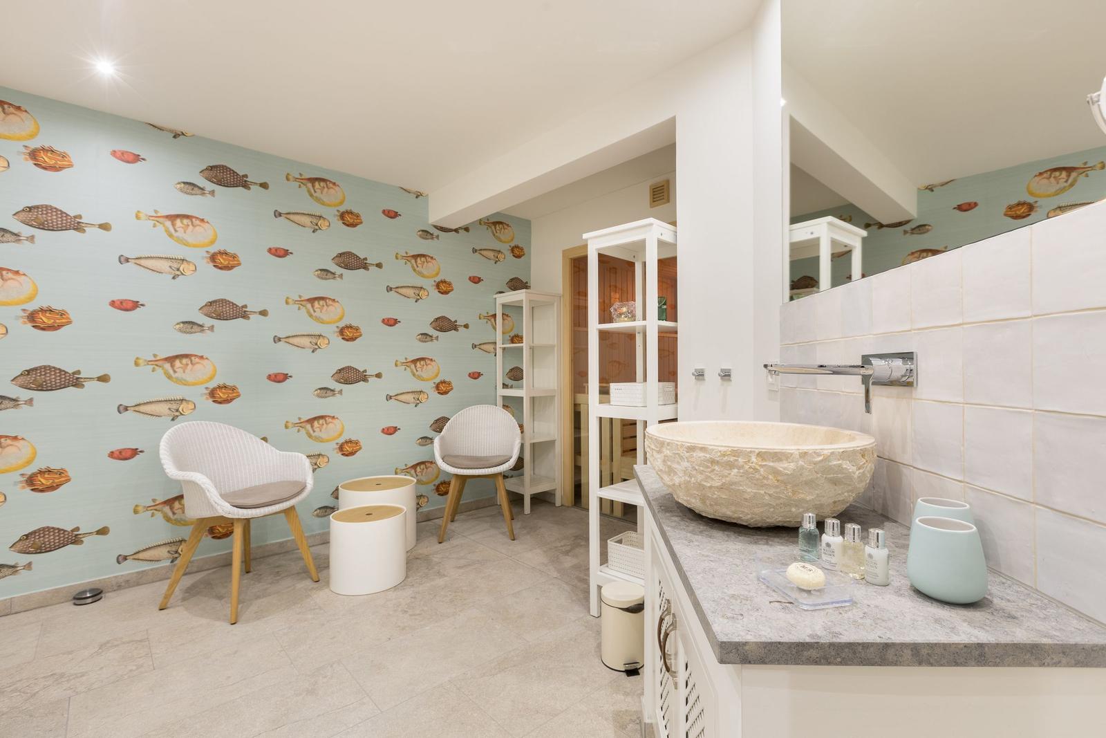 Badezimmer mit Fischtapete, Steinwaschbecken und weißen Möbeln.