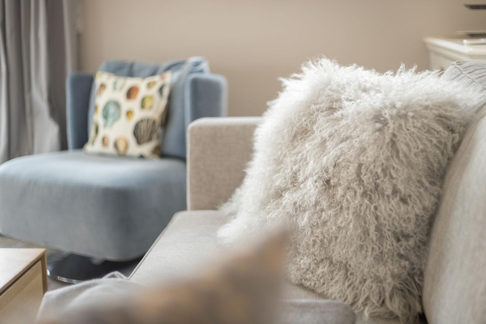 Ein Sofa mit flauschigem Kissen und ein Sessel mit Musterkissen.