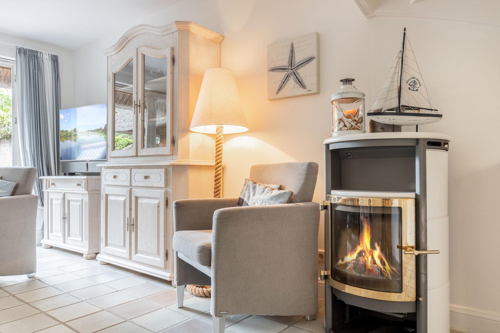 Wohnzimmer mit Kamin, Sessel und Fernseher. Dekoration mit Segelboot und Sternfisch.