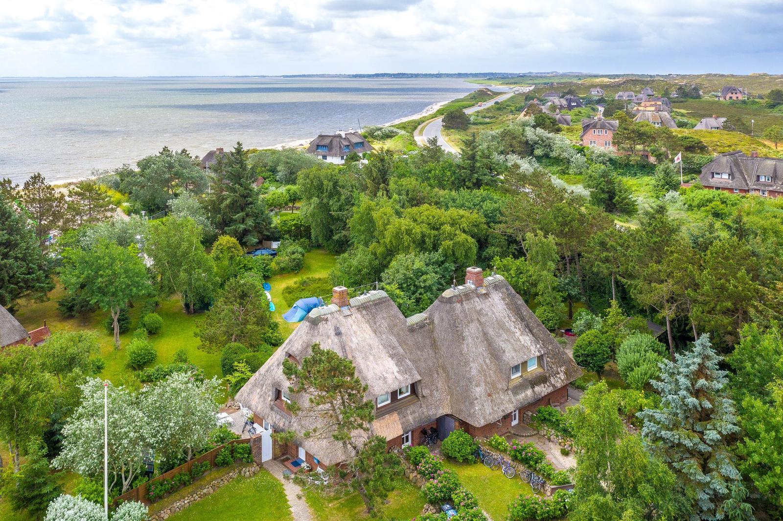 Dorfhaus mit Strohdach, umgeben von Grünflächen und nah am Strand.
