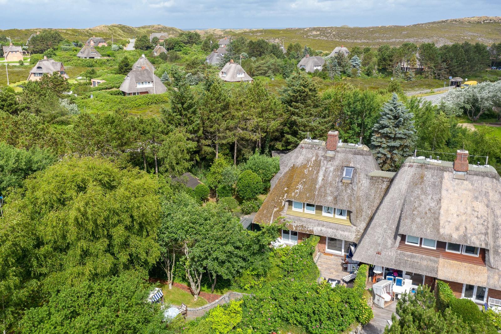Dorf mit strohgedeckten Häusern und grüner Umgebung