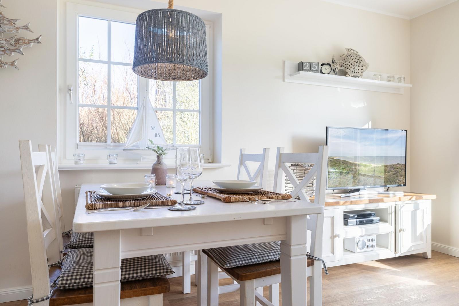 Dining room with table, chairs, and TV. Window with sailboat model.